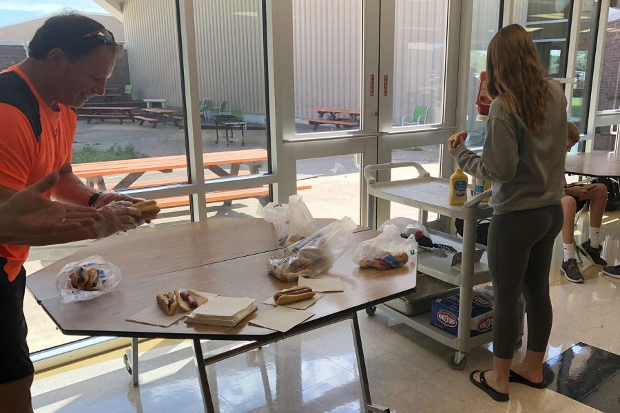 Pastor Rick Neubauer passes out hotdogs for FCA while Maddy Muhlig (10) add condiments to her hotdog.