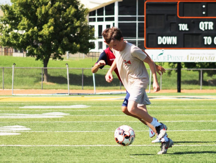 Freshman Kalvin LaPlant dribbles through the defender on the first day of fall sports tryouts. The boys soccer team practiced on the Hiller Stadium field after school.  


