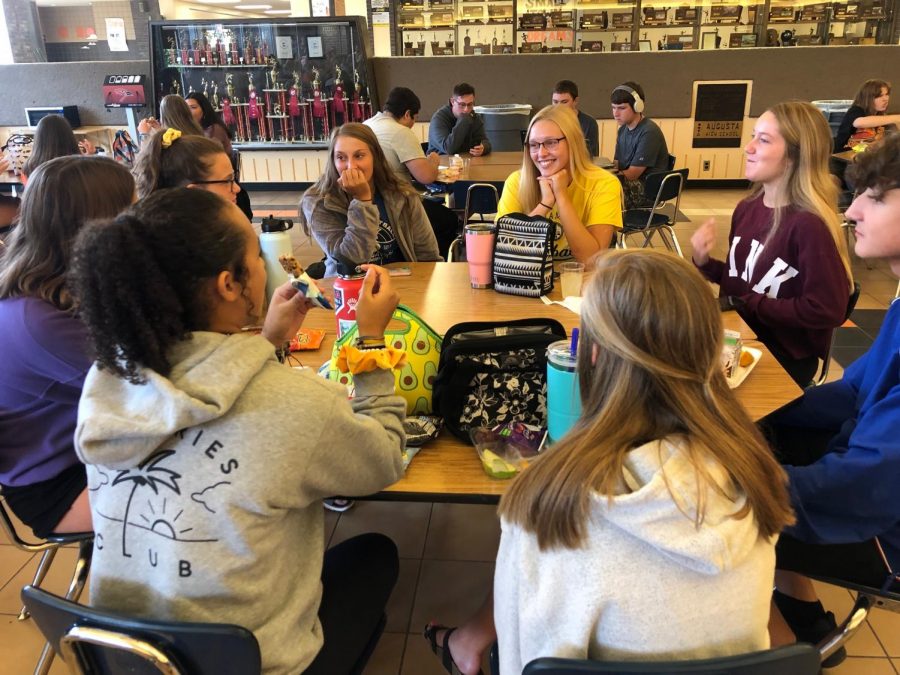 A group of students both eating and socializing at the same time. These students were laughing at a joke junior Ashlyn Bowen made.