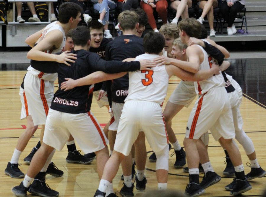 Screaming+their+team+chant%2C+the+Orioles+sway+back+and+forth+around+sophomores+Josh+Burton+and+Morgan+Livingston+while+they+perform+the+Futsal+Shuffle.+The+team+advanced+to+the+second+round+of+the+state+basketball+tournament%3B+however+their+season+was+cut+short+due+to+concerns+about+COVID-19.