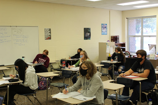 Students go over notes while wearing masks and social distancing in their third block math class. Students and teachers are supposed to social distance whenever possible.
