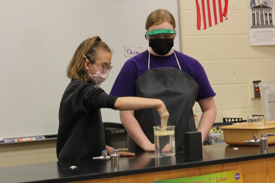 During the advanced chemistry magic show, senior Macie Goodmanson shows an elementary student a science experiment. Even during the chemistry show, students still had to wear masks, and some students and teachers hope that the mask mandate will hopefully be gone next year. Photo by Paige Harrington