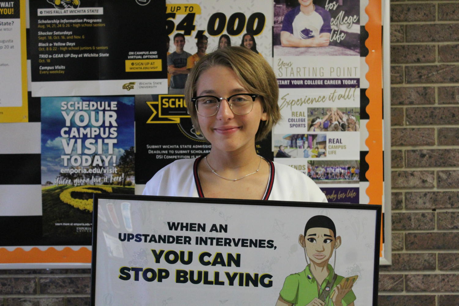 Sophomore Emma Neuschafer showcases the bullying poster found in the counselor's office. This supports the bullying awareness cause that the student body in AHS has currently been taught since the first early stages of education.