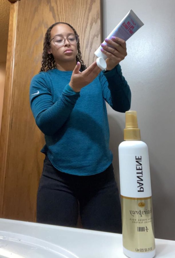 To prepare for school, senior Adrian Walker puts product into her hair as part of her hair care routine. Before she was old enough to take care of her own hair, her mother learned how to care for it.