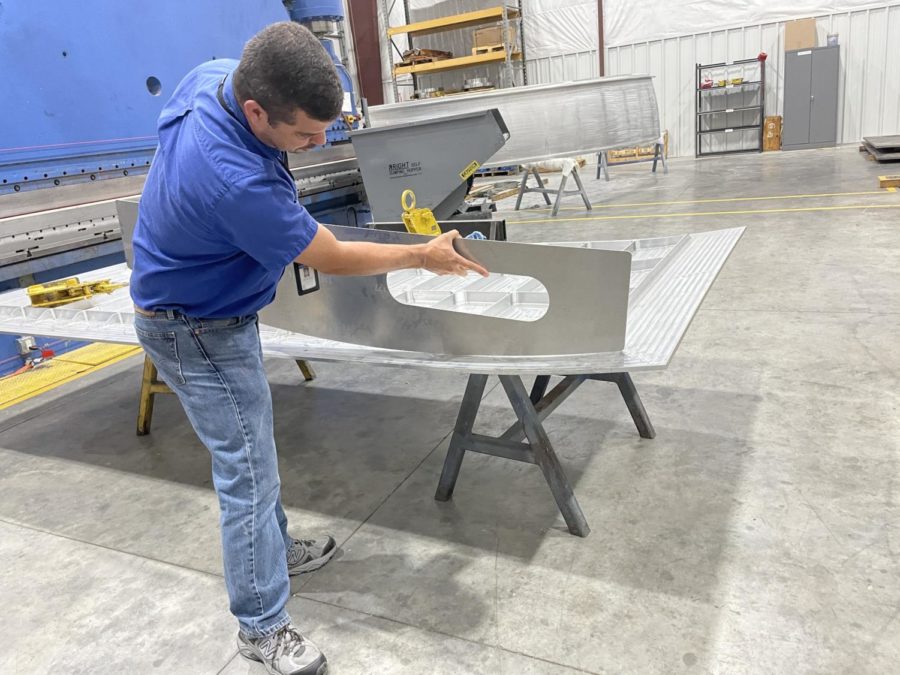 Vice president of engineering and technical services at D-J Engineering Ryan Hernandez demonstrates how they use a template to form a barrel panel. A barrel panel surrounds and helps protect the inner gas tank inside of a spaceship.