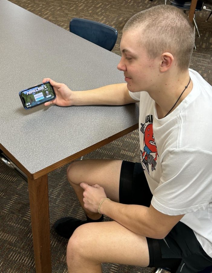 Sophomore Cooper Stueven loads “Minecraft up on his phone. Stueven was getting on the realm to continue his castle that Cooper Stueven and other students helped build.