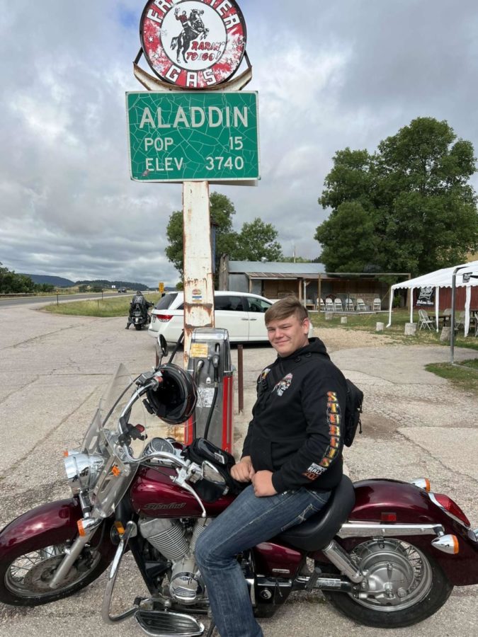 Junior Collin Jansen sitting on his motorcycle in Aladdin, Wyo. He stopped for gas and had his dad take the picture to show the population size of Aladdin, which was only 15.