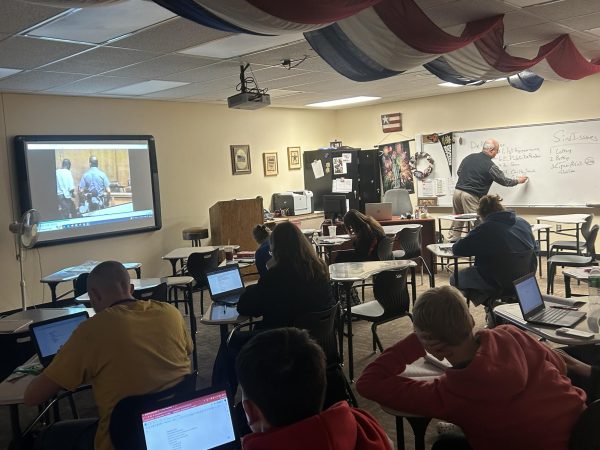 Social studies teacher Jeff Regier’s 3A class watches a video to learn about the real-world usage of amendments. Regier had many more students during the first semester, and now he has very few students for the second semester. 