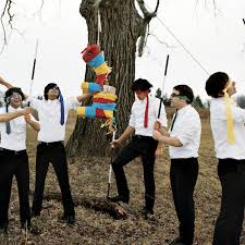 Members of Tally Hall circle around a pinata, using their ties as blindfolds. Tally Hall was a band known for their harmonization, messages hidden in or around their songs, and their colored ties, which each member used as a way to be recognized. Photo courtesy Spotify