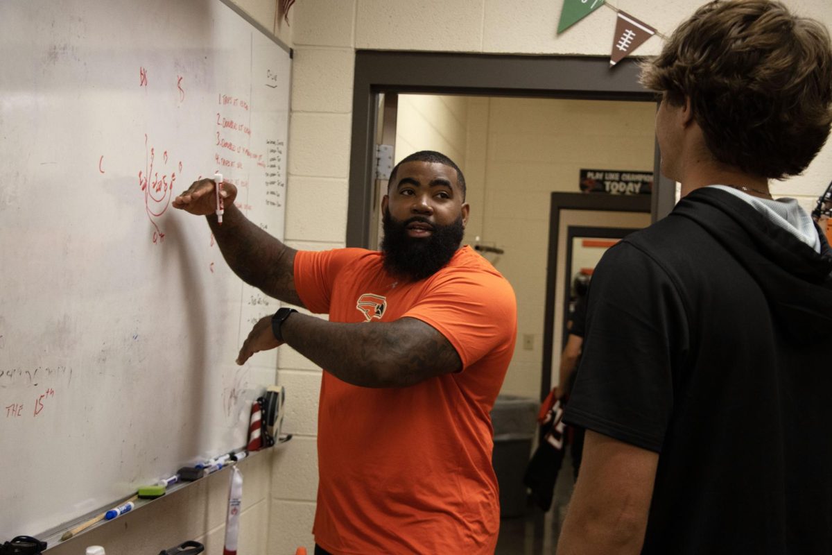 Assistant football coach and behavior liaison Dreamius Smith describes a play he drew on the board to junior Cade Camac. Smith appreciates Augusta’s single level building because his high school, Wichita Heights High School, is three stories.