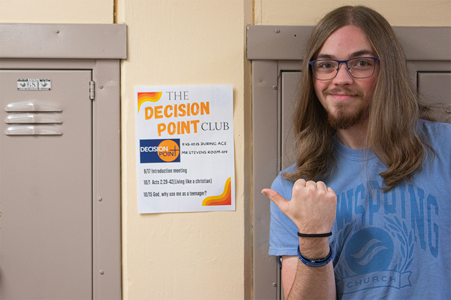 Senior Elijah Quiring points out the new flyers for The Decision Point club. Quiring leads these club meetings every two weeks in room 109.