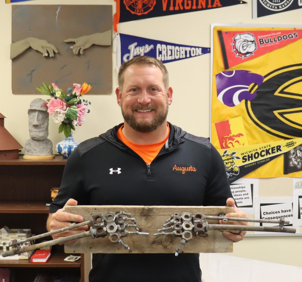 Social studies teacher Brad Raine holds up a past rendition of The Hand of God. Raine was surprised by the uncommon style; students usually opt for a more artistic route. 