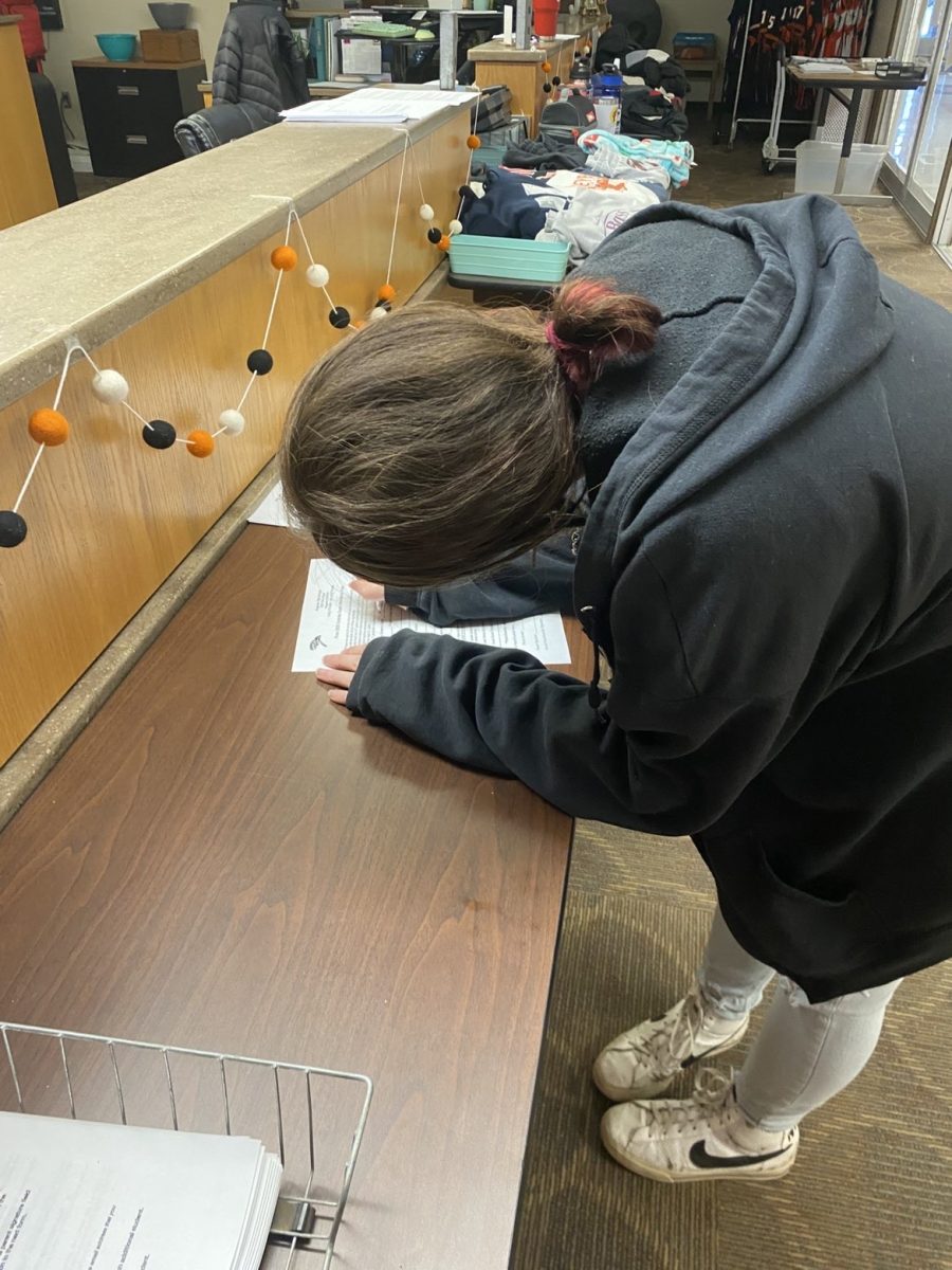 Senior Savanna Rosenbaum signs a form to invite an out of town guest to attend prom with her. Forms can be found in the main office.  
