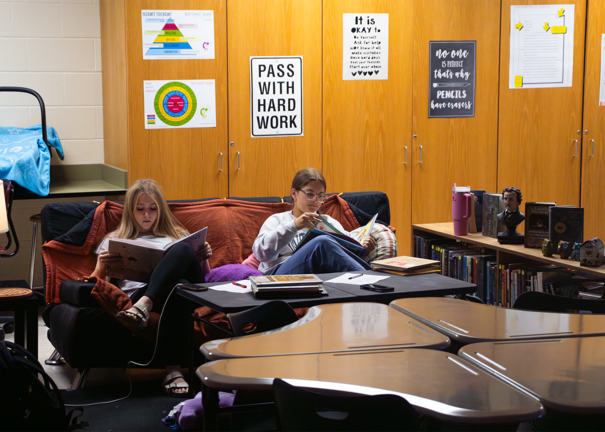 Sophomore Kaylee McConaghie and freshman Blyss Gilliam sit on a couch reading children's literature for family studies teacher Megan Springs. The couch they sit on was previously in the old room but was not used as frequently. “I think its cause it was so crammed and didn’t feel as freeing in my old room,” Springs said.